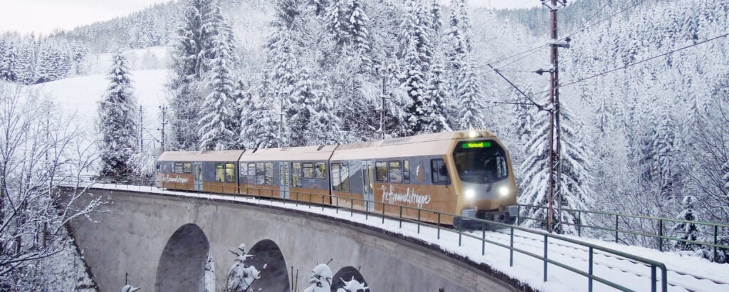 Mariazellerbahn driving over a bridge in snowy landscape