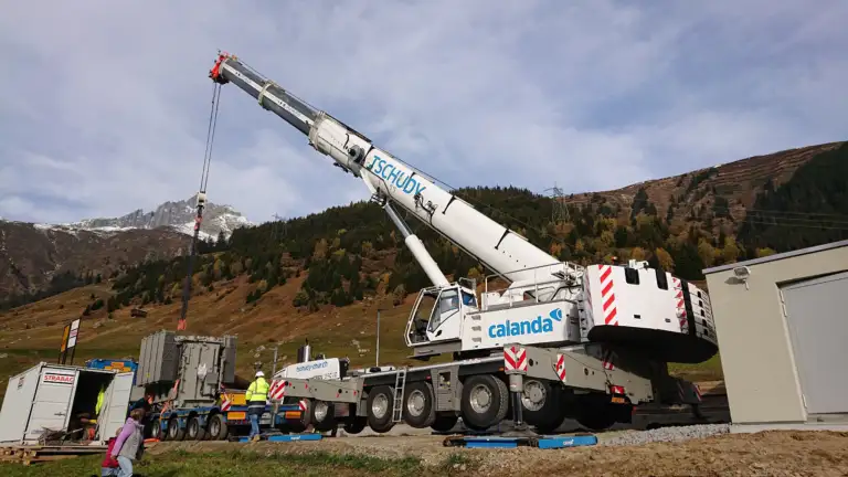 Ein Trafo wird von einem Lastwagen von einem Kran abgeladen
