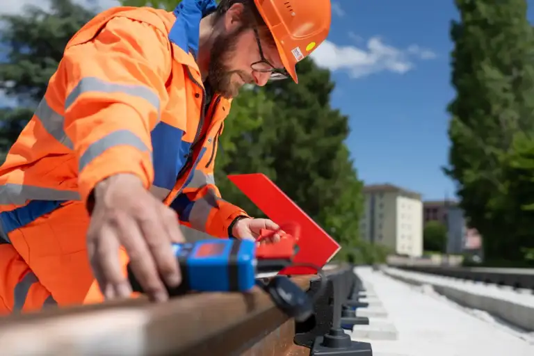 Zwei Enotrac Mitarbeitende in einem Gleis arbeitend messen mit einem Multimeter