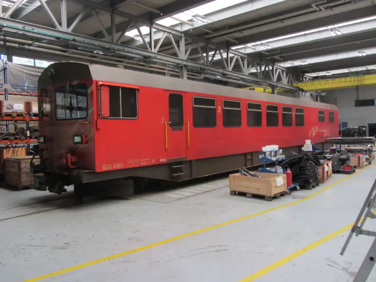 Red driving trailer of the Furka Railway / Matterhorn Gotthard Railway in a maintenance workshop.
