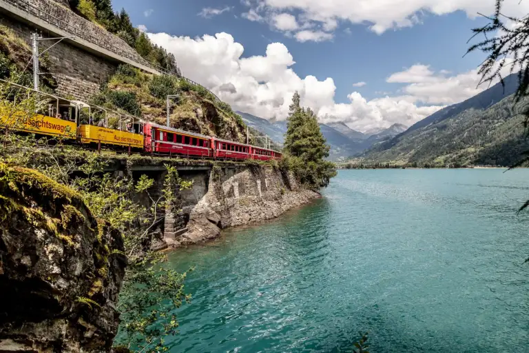 Offene Aussichtswagen der RhB an einem See in den Alpen