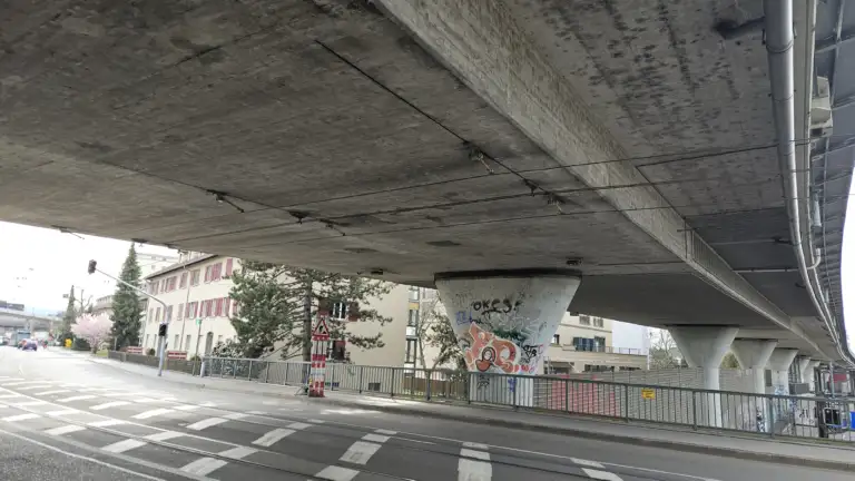 Ansicht von unten an eine Brücke. Zu sehen sind die Tramfahrleitungen