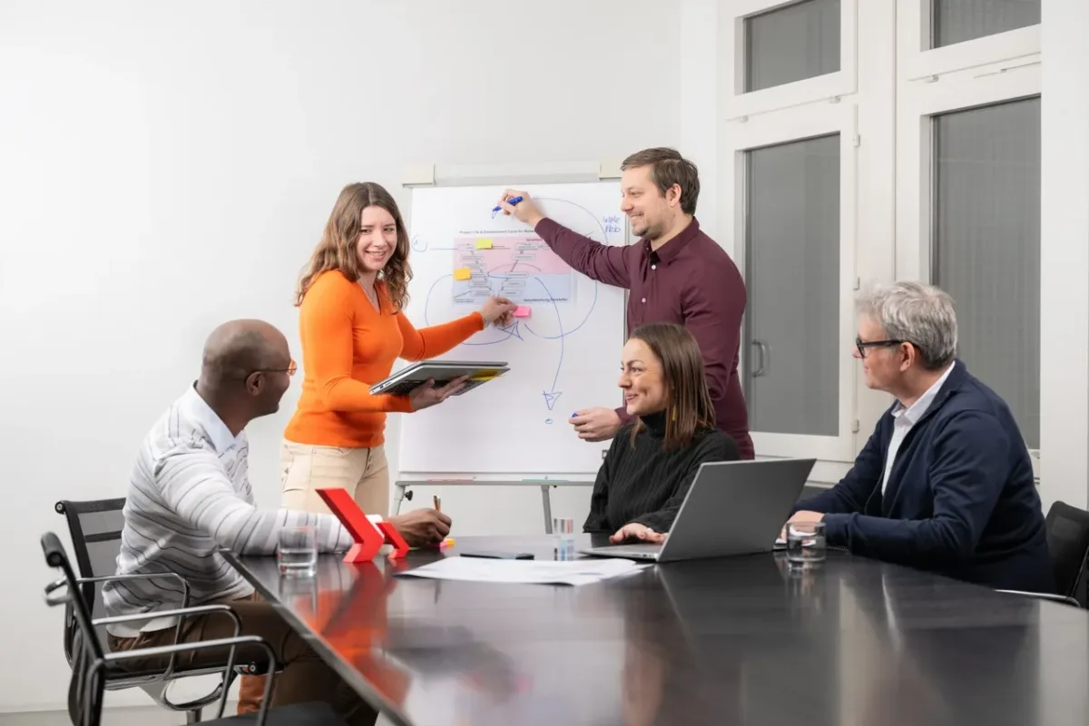 Enotrac Mitarbeitende diskutieren eine Idee am Whiteboard